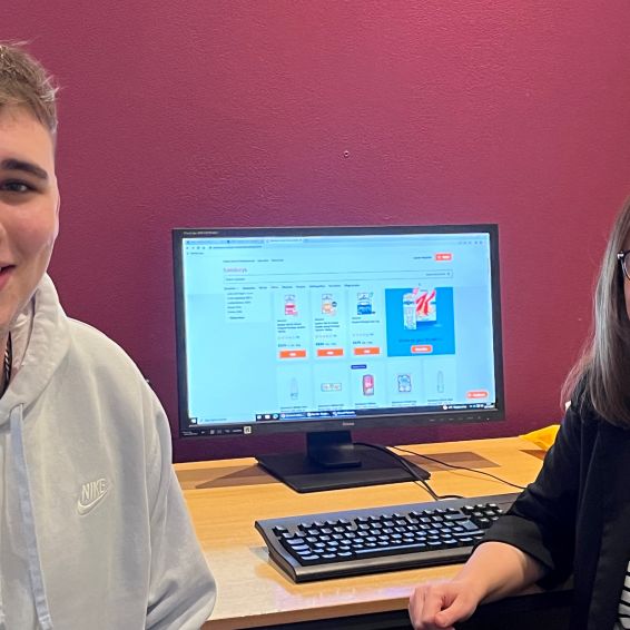 Male and female sat in front of a computer screen which displays food items on a supermarket website