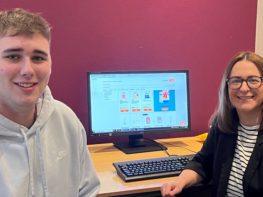 Male and female sat in front of a computer screen which displays food items on a supermarket website