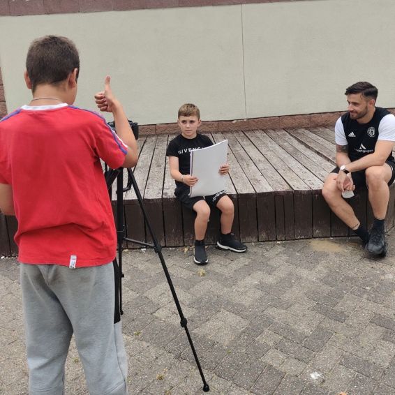 Three boys learn to film and present during workshops